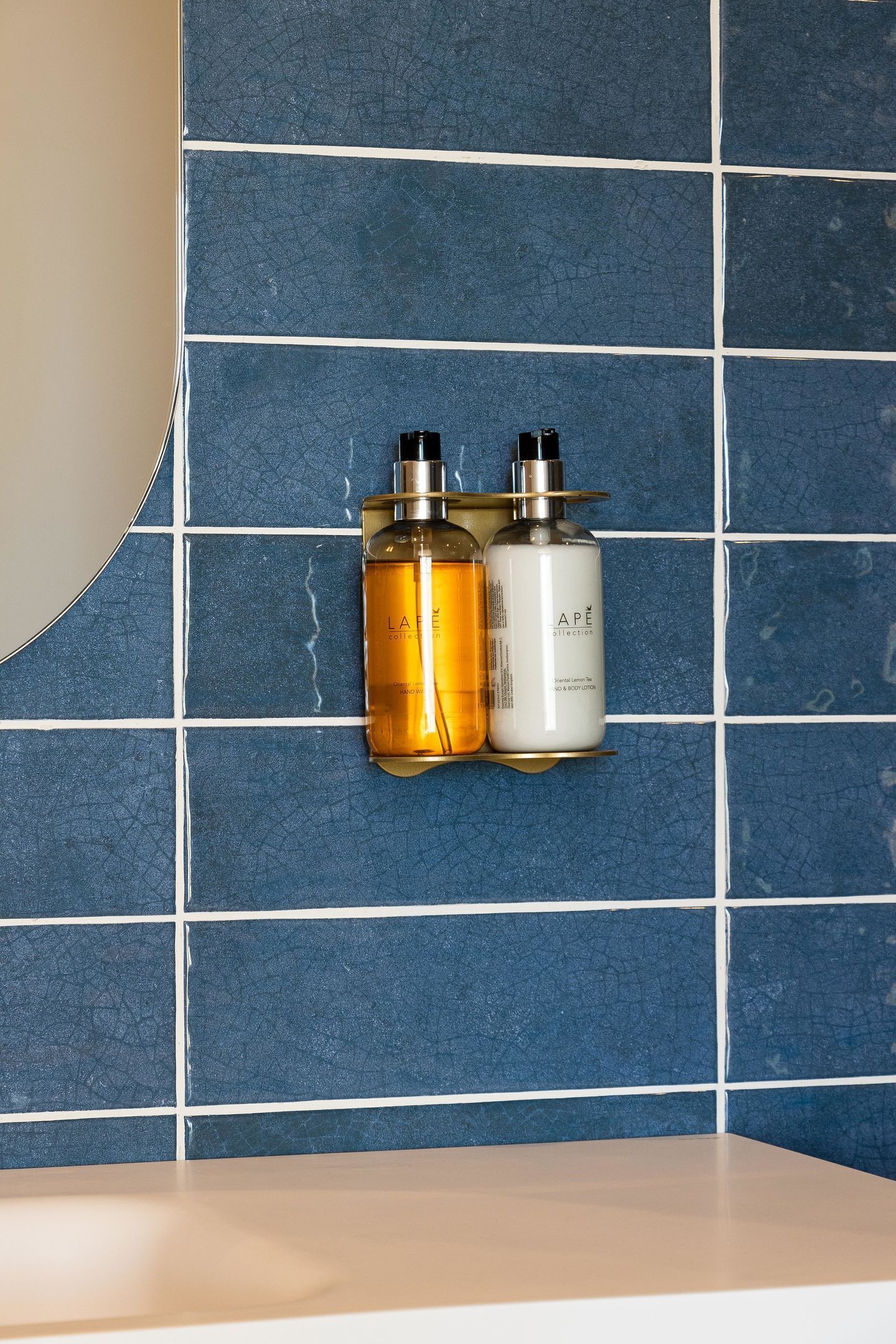 A bathroom with a blue tiled wall and a white countertop.