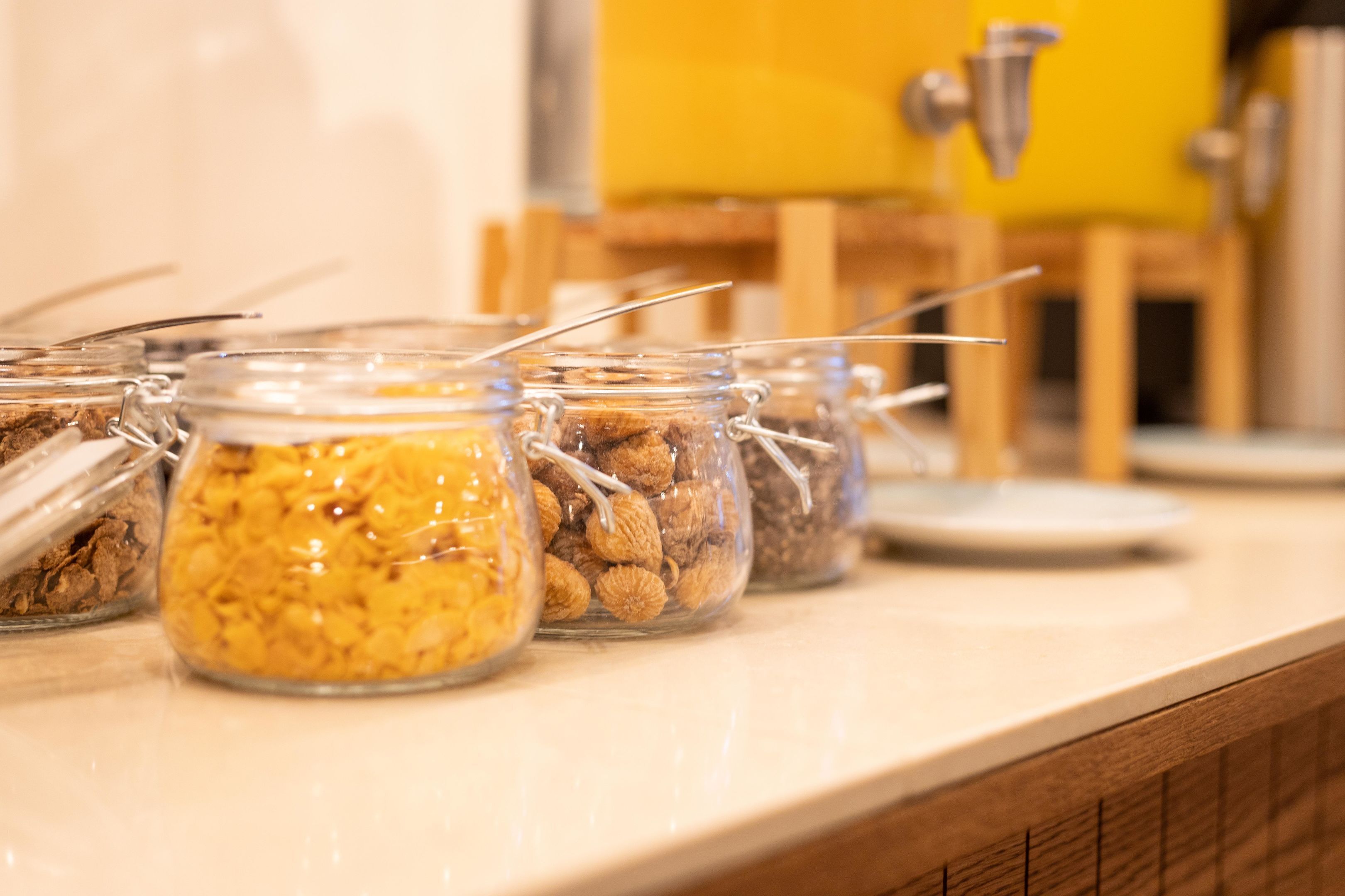A row of glass jars with metal clasps containing various food items on a countertop.
