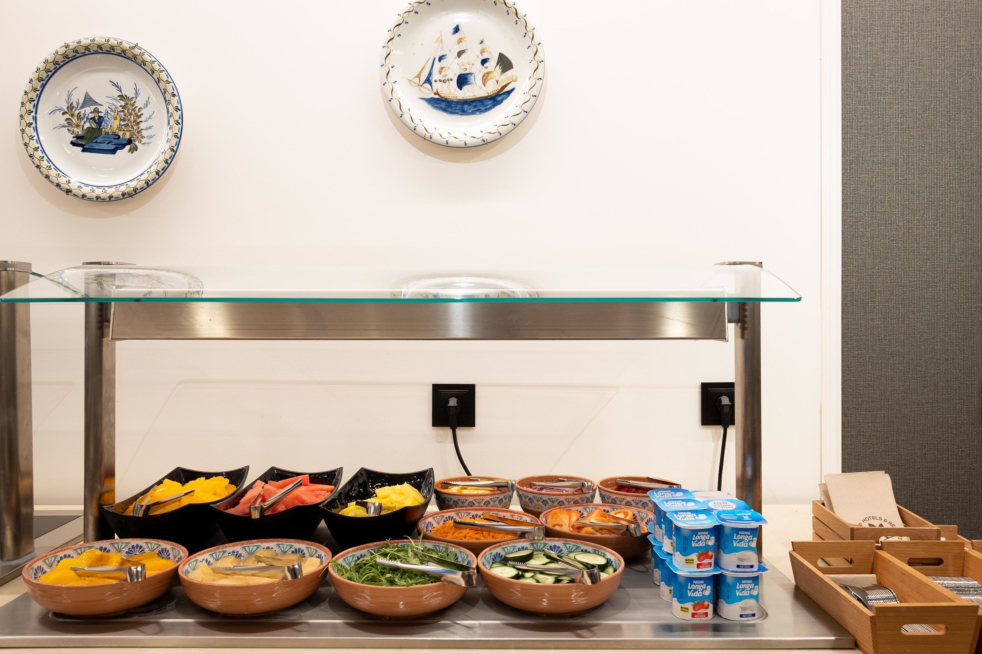 Une table de buffet garnie de divers plats et accompagnements, entourée d’assiettes décoratives accrochées au mur.