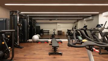 Un gimnasio con equipo de ejercicio, una banca y un espejo.