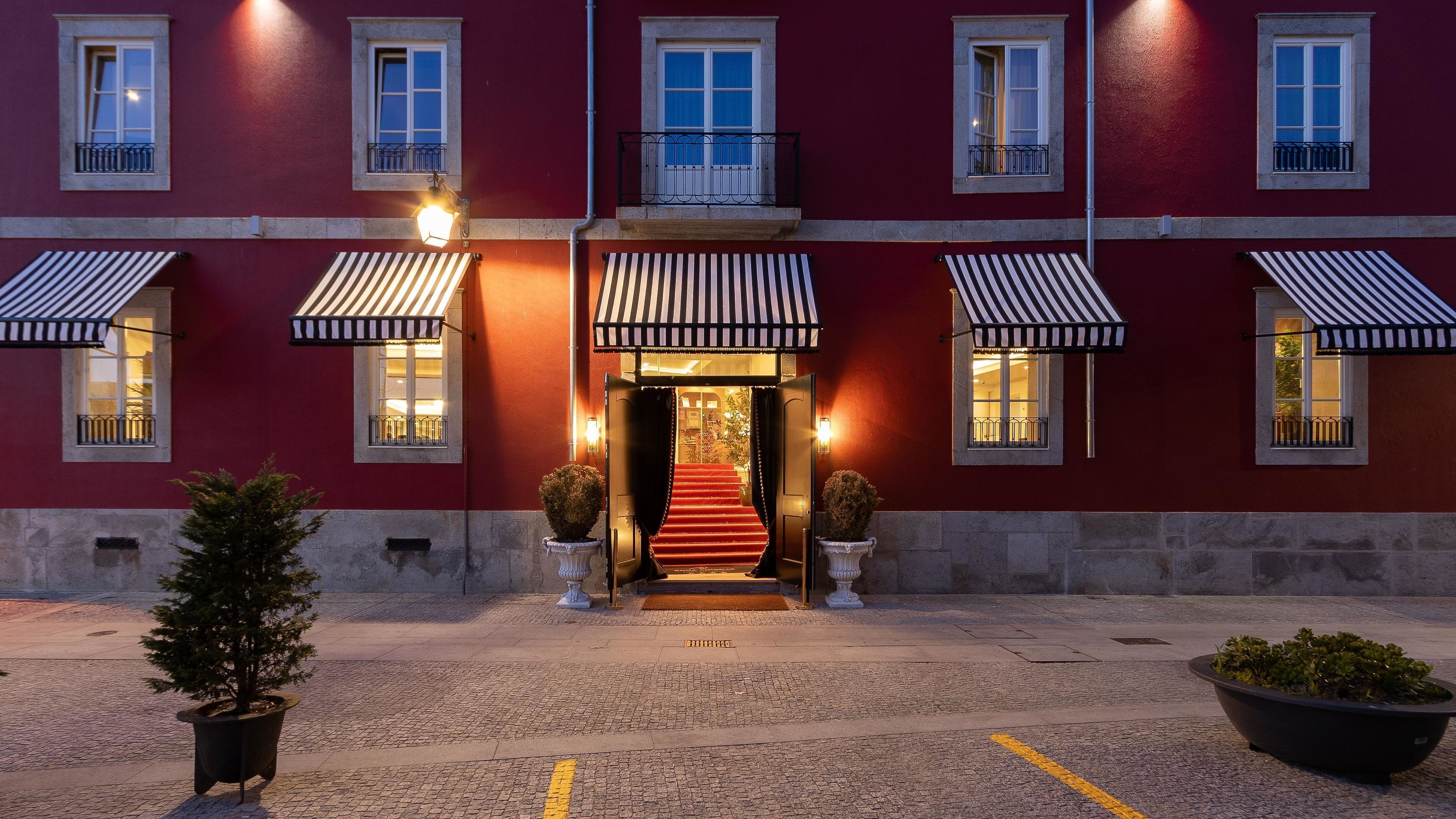 A hotel entrance with a red facade, a central staircase, and multiple awnings.