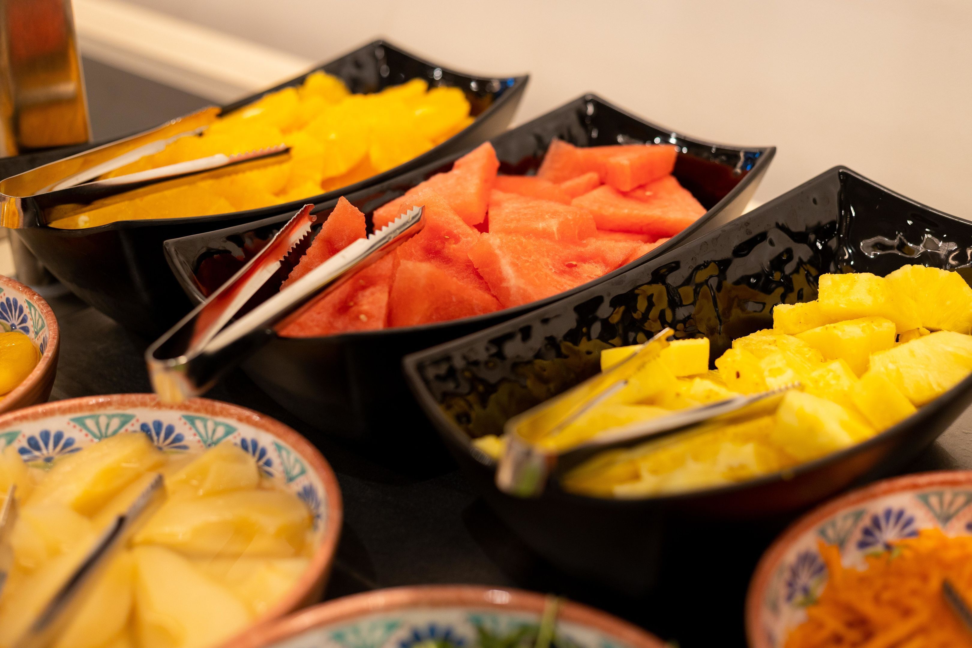 A buffet with various fruits including watermelon, pineapple, and mango.