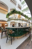 Una zona de bar con barra circular, varias opciones de asiento y vistas de los niveles superiores del edificio.