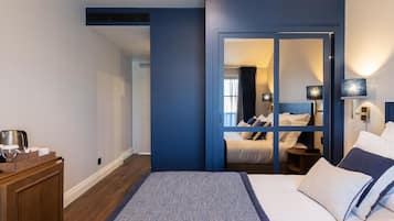 A hotel room with a large bed, a wooden side table, a mirror, and a wardrobe.