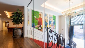 A hotel lobby with a wooden floor, a red carpeted staircase, a large potted plant, and a chandelier. - AP Dona Aninhas  (Viana do Castelo)