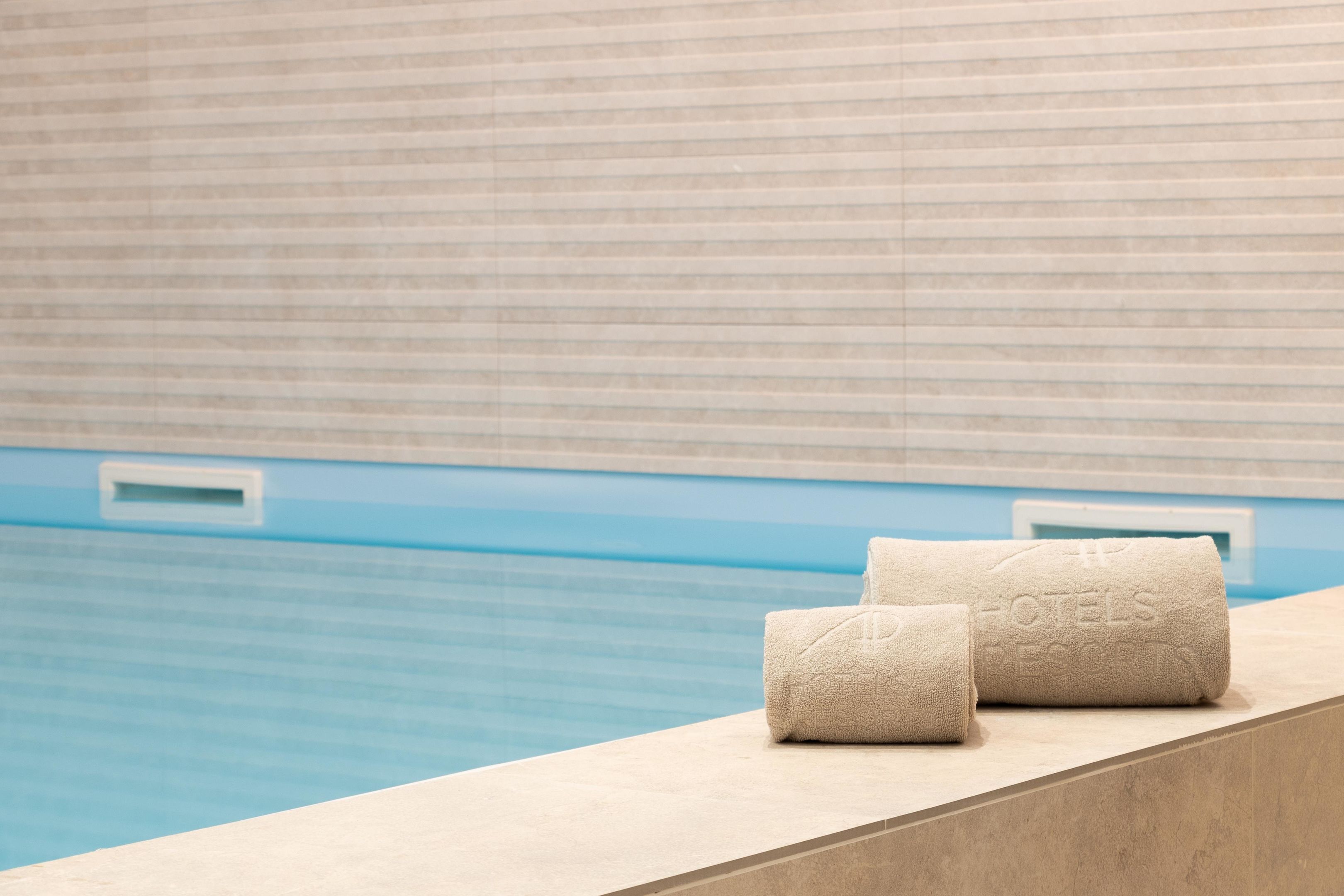 A poolside area with two towels placed on a ledge.