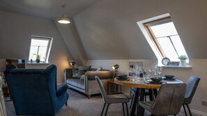 A loft-style room with a dining area, a sofa, and a blue armchair. - Old Distillery Apartment in Fort William (Fort William)