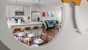 Una cocina moderna con armarios blancos, una isla central y un comedor con una mesa redonda y sillas.