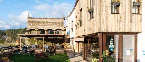 A rustic building with a covered outdoor seating area and a glass storefront.