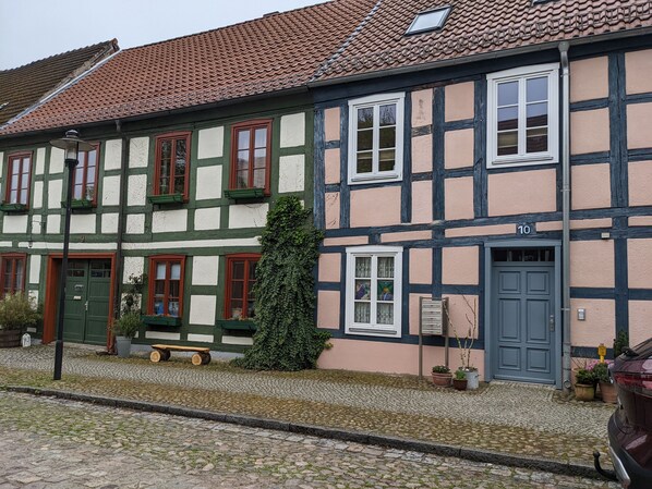 A traditional half-timbered building with a cobblestone street in front. - Vacation apartment with a natural garden on the outskirts of the village. Beach and forest 500 meters away (Templin)