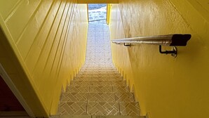 A narrow stairway with yellow walls and a tiled floor leading to a bright outdoor area. - Seaside apartment 4 pers Bananier Capesterre B-E (Trois-Rivières)