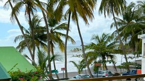A view of a beach with palm trees and a building with a green roof. - Seaside apartment 4 pers Bananier Capesterre B-E (Trois-Rivières)