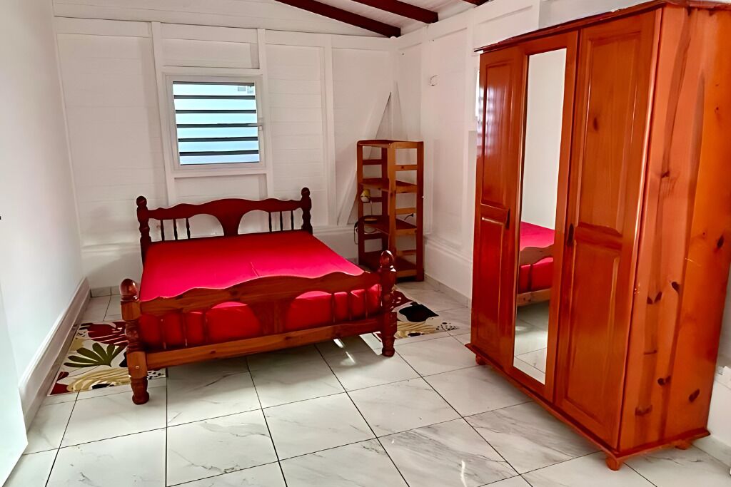 Un dormitorio con una cama de madera, un armario y una ventana con persianas.
