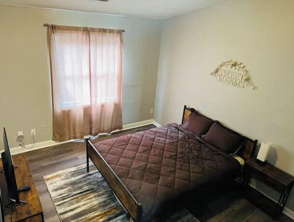 Relax in a serene bedroom with a large bed, a nightstand, and a TV.
