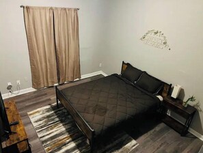 Relax in this serene bedroom with a large bed, a bench, and a nightstand featuring a lamp.