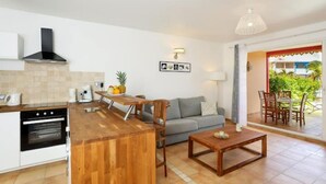 A compact kitchen with a wooden island, a built-in oven, and a dining area with a table and chairs. - SALT 5: swimming pool, direct access to Orient Bay beach (Collectivité de Saint-Martin)