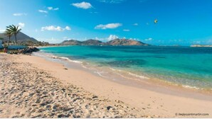 A beach with clear turquoise water, sandy shore, and mountains in the background. - SALT 6: swimming pool, direct access to Orient Bay beach (saint Martin)