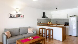 A compact living space with a kitchenette, a grey sofa, a wooden coffee table, and a small island with stools. - SALT 6: swimming pool, direct access to Orient Bay beach (saint Martin)