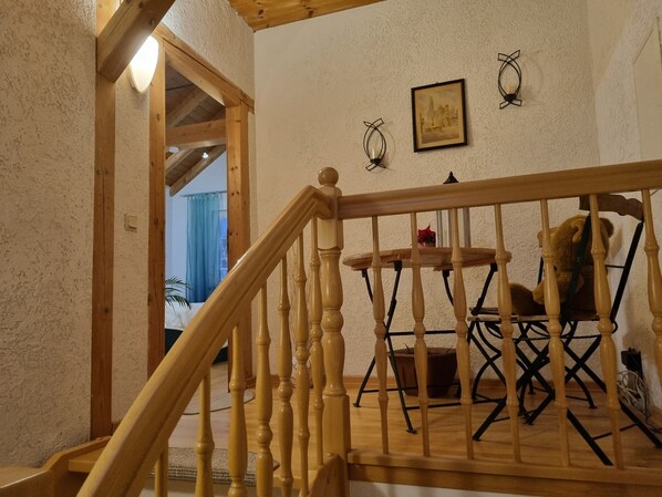 A wooden staircase with a railing leading to a room with a wooden table and chairs.