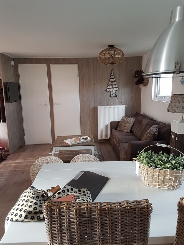 A cozy living room with a brown leather sofa, a white table, and wicker furniture. - The charmingly decorated Chalet Florence 2 near the sea in Serooskerke (Serooskerke)