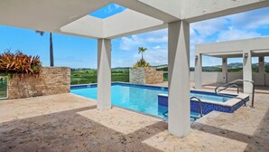 Un espace piscine offrant une vue dégagée sur le paysage, avec des murs en pierre et une partie abritée.