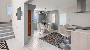 Une cuisine moderne dotée d’une cuisinière intégrée, un coin repas avec une table et des chaises, et un escalier menant à un autre niveau.
