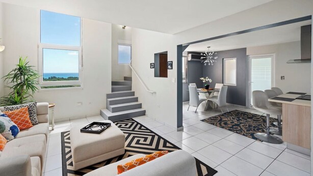 Un appartement moderne avec un escalier menant à un balcon, un coin repas et une cuisine.