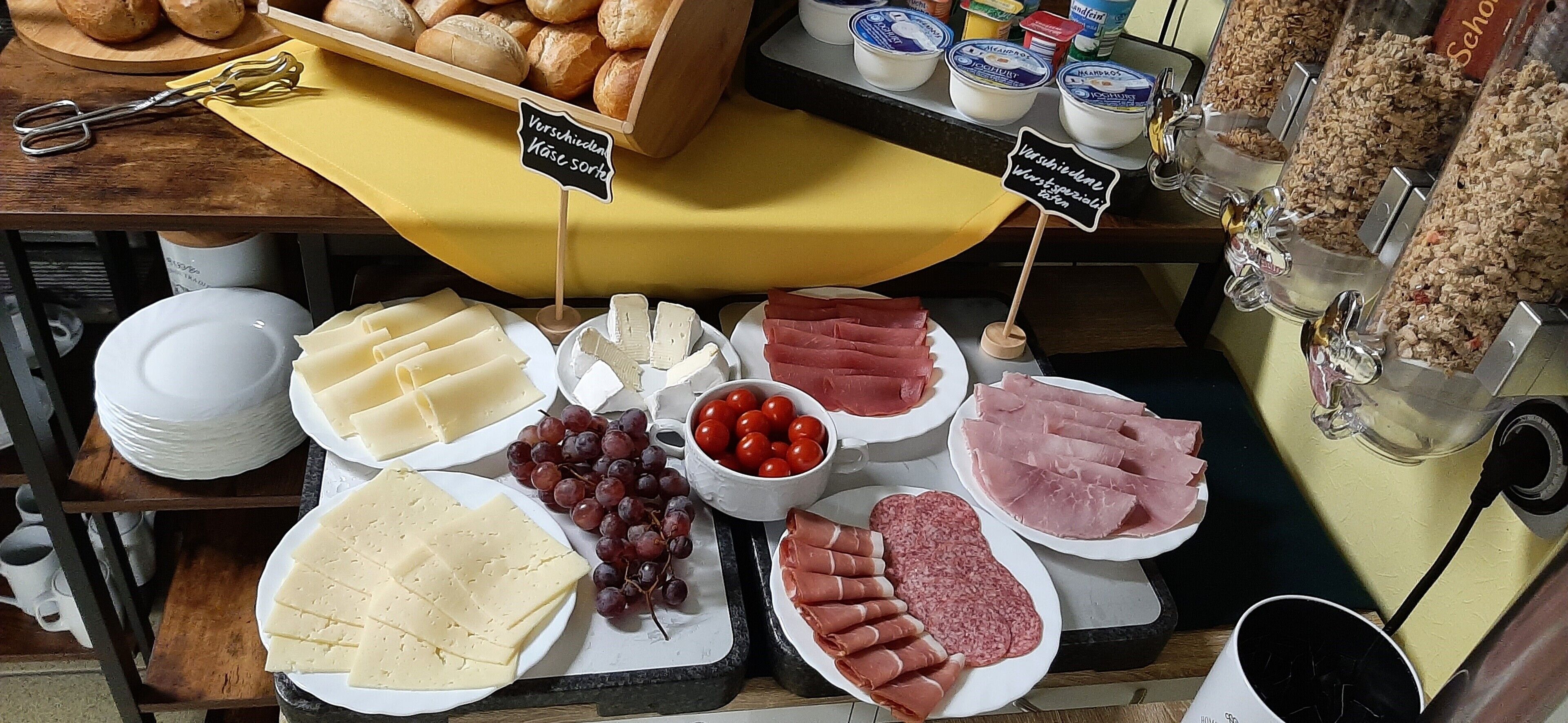 Eine Auswahl an Käse, Fleischwaren und Obst auf einem Markt.