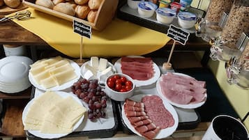 Eine Auswahl an Käse, Fleischwaren und Obst auf einem Markt.