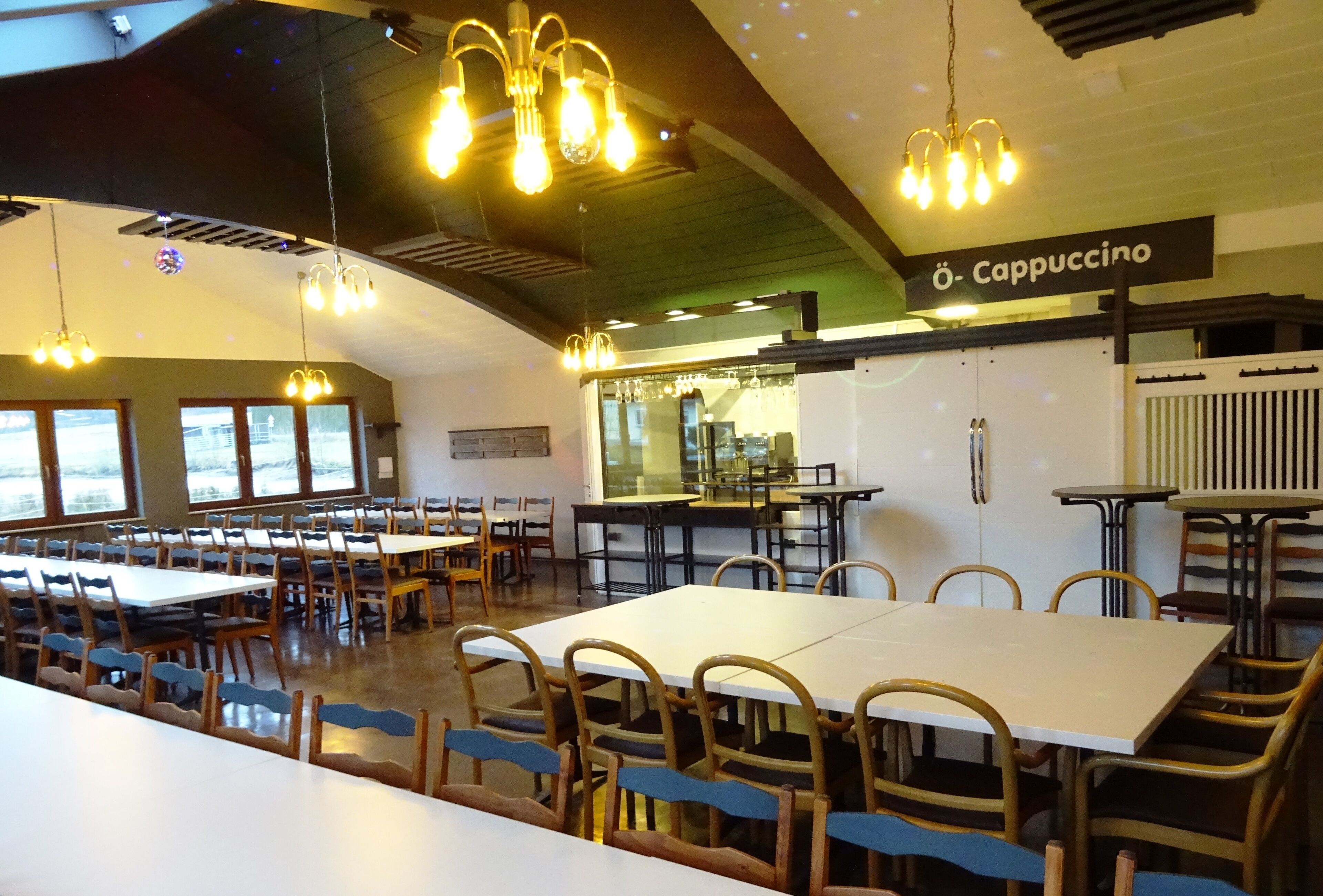 Un comedor amplio con varias mesas y sillas, una estación de café y vistas amplias a través de grandes ventanales.
