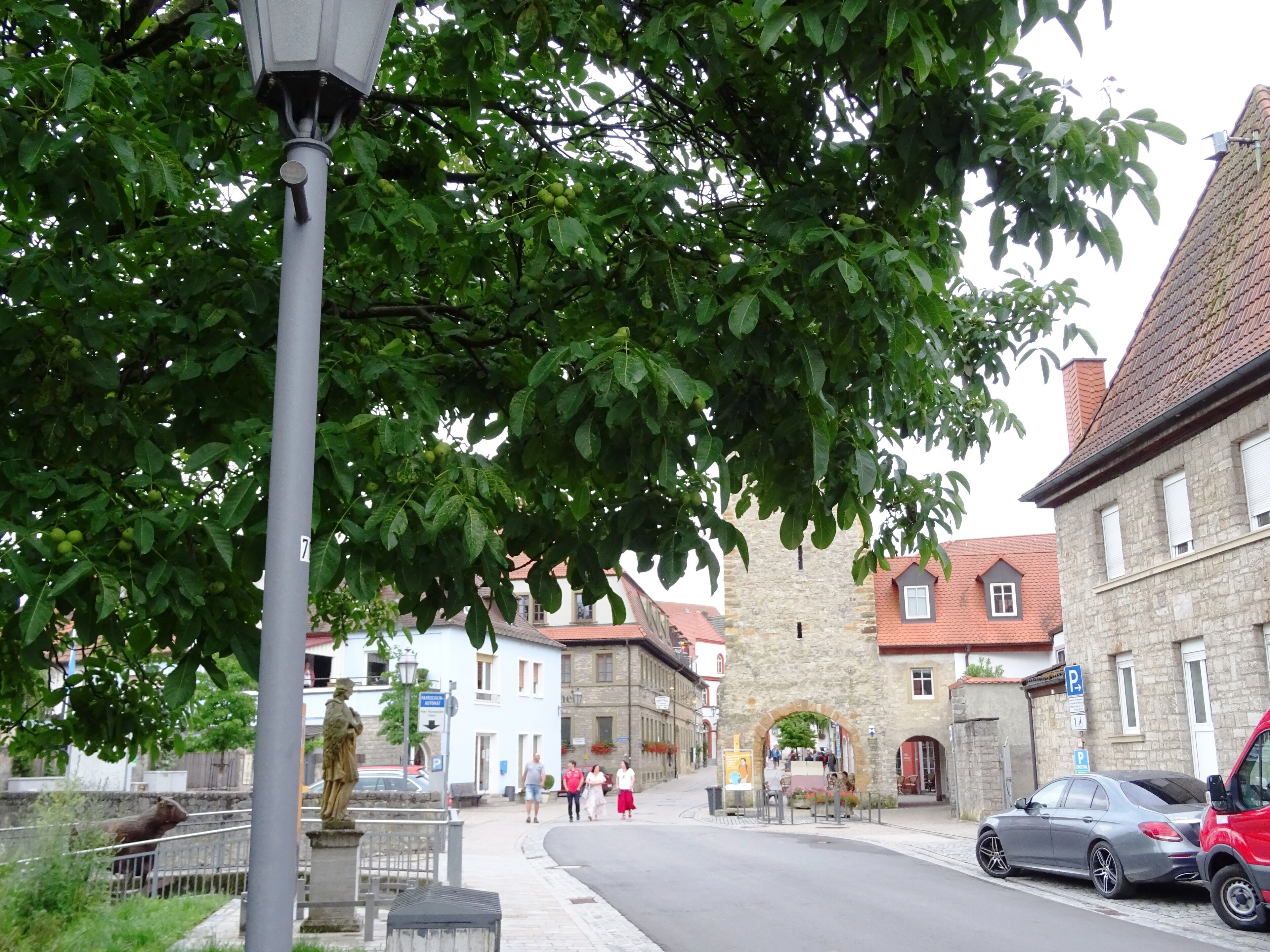 Une rue bordée d’immeubles en pierre, avec une statue et un lampadaire.