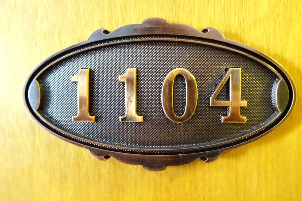 A brass house number plaque with the number 1104 on a textured background.