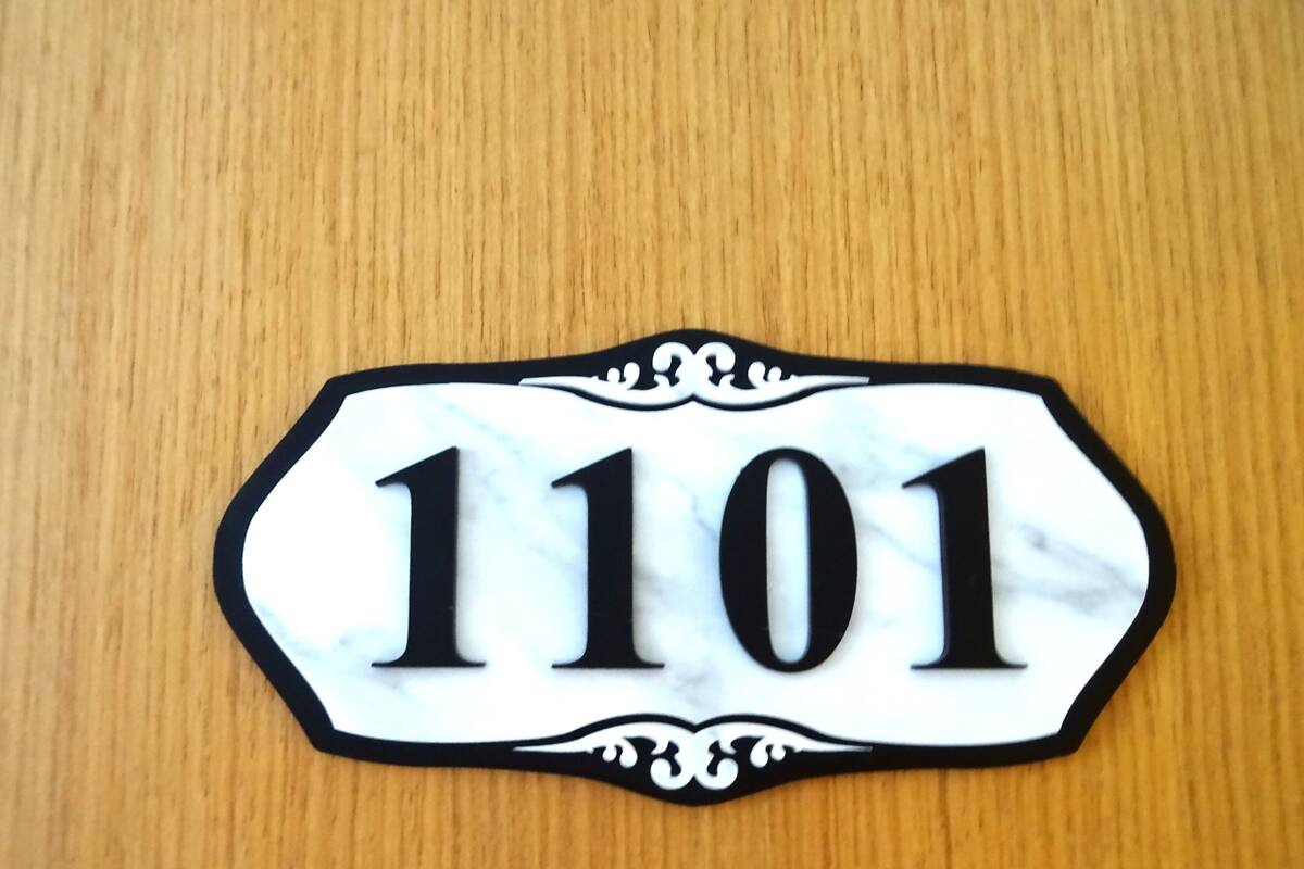 A house number sign with the number 1101 on a wooden background.