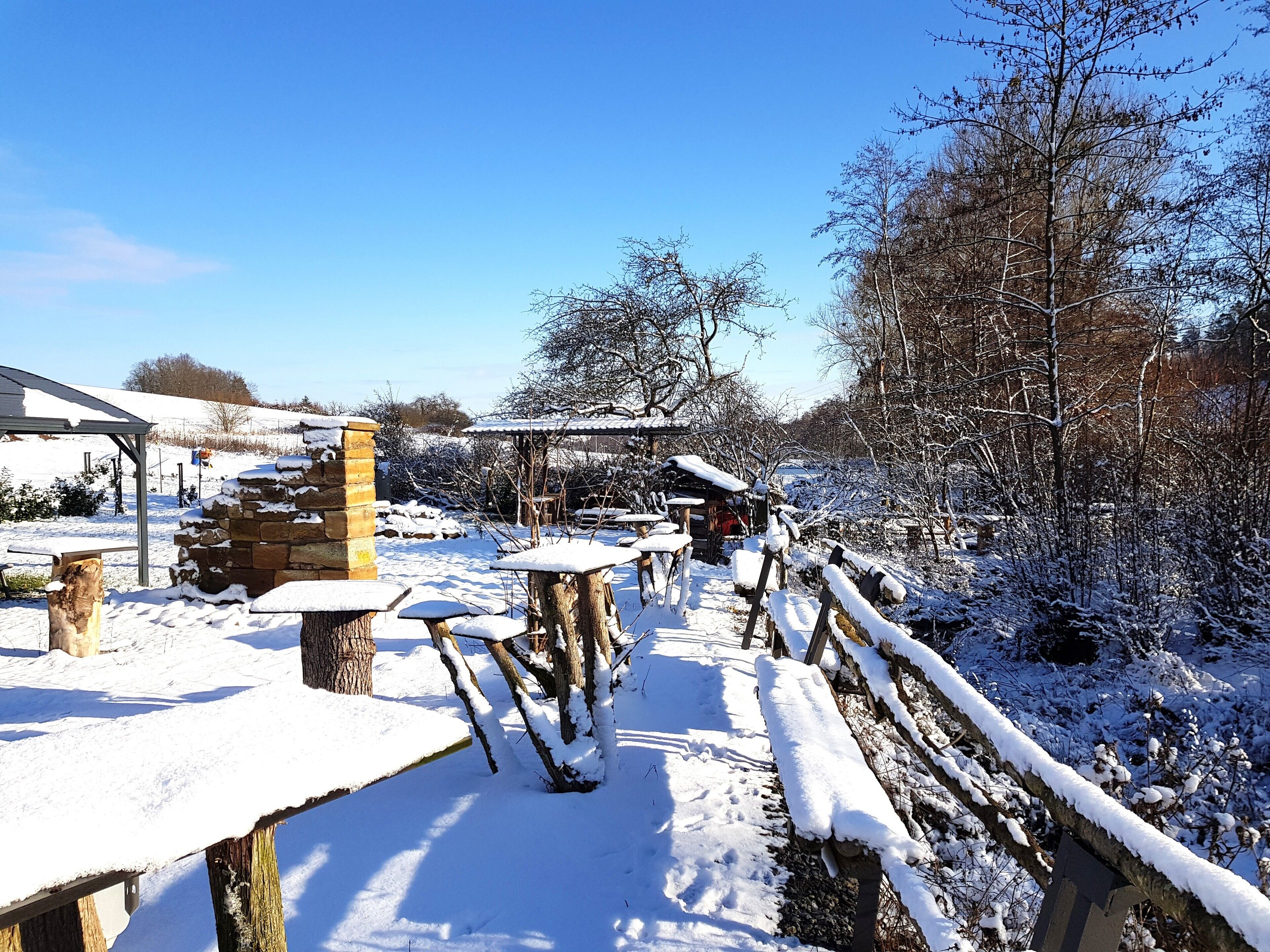 Schneebedeckte Freifläche mit Steingebäuden und Holzbänken.
