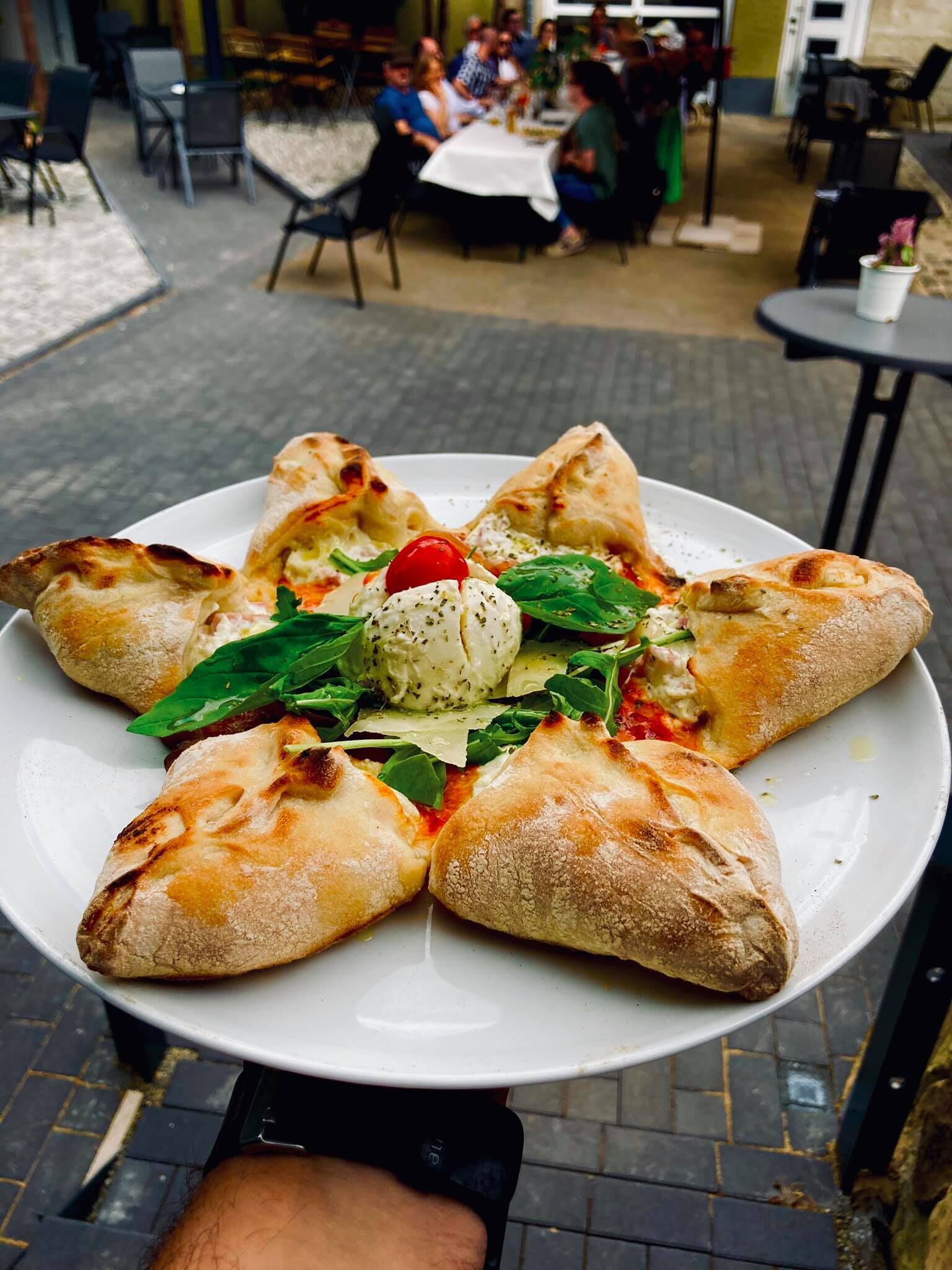Une assiette remplie de nourriture, surmontée d’une boule de crème glacée et d’une cerise, que tient une personne.