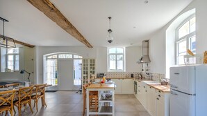 A spacious kitchen with a central island, white cabinetry, and a large window providing natural light.