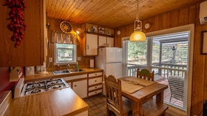 Una cocina con armarios de madera, estufa y una mesa de comedor con sillas.