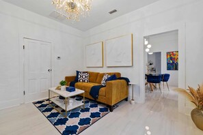A modern living room with a sofa, coffee table, and artwork on the wall.