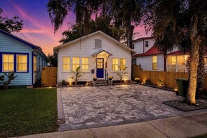 A two-story house with a front porch, a blue door, and a paved driveway.