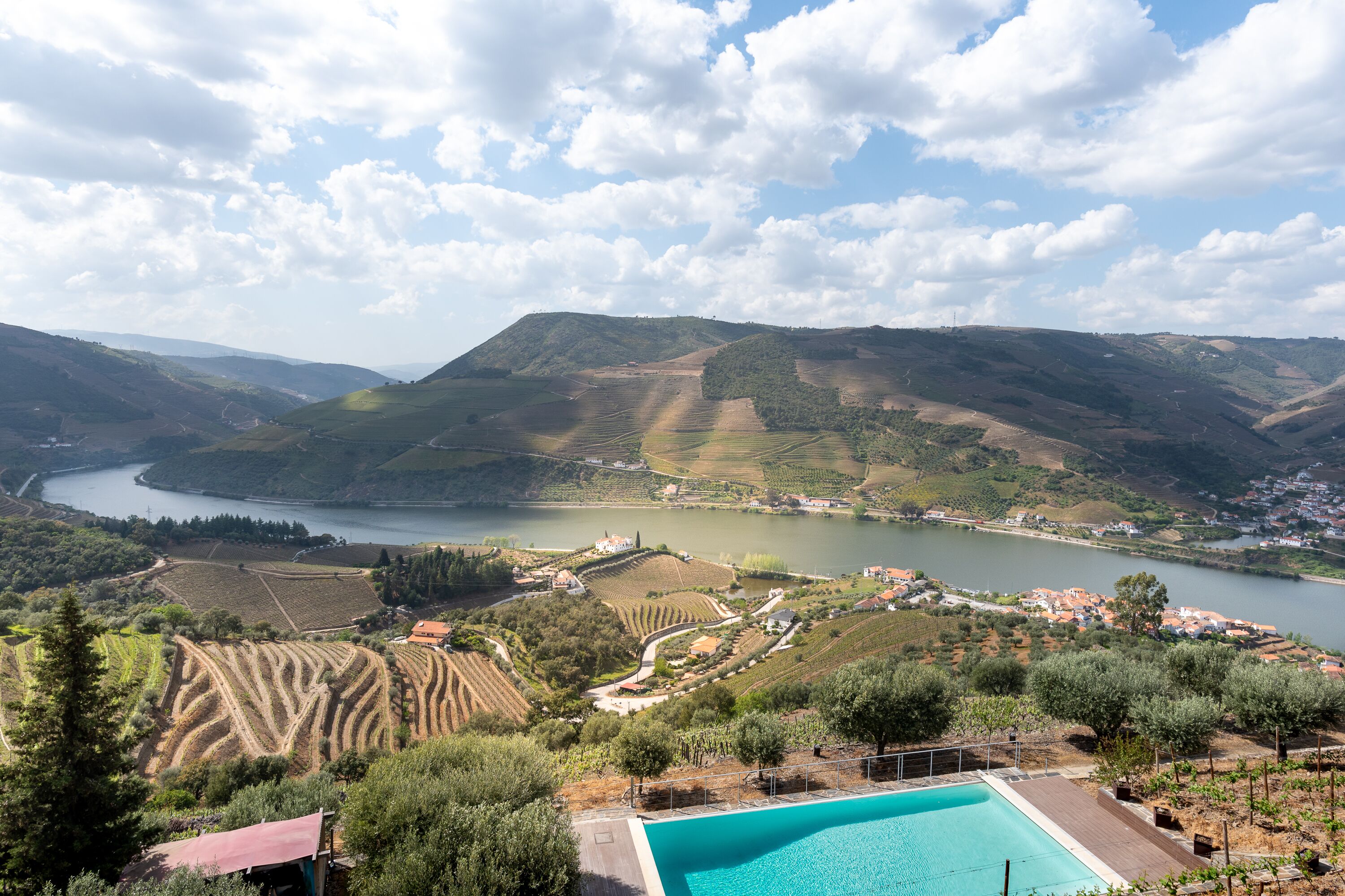 A pool with a view of terraced vineyards and a river.