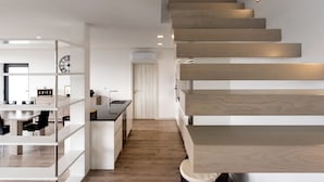 A modern kitchen with a central island, wooden staircase, and a dining area with a glass partition. - Feel Discovery Alvim's Douro (Armamar)