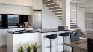 A modern kitchen with a central island, bar stools, and a staircase. - Feel Discovery Alvim's Douro (Armamar)