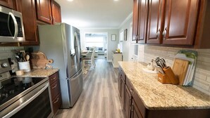 Una cocina con armarios de madera, electrodomésticos de acero inoxidable y encimera de granito.