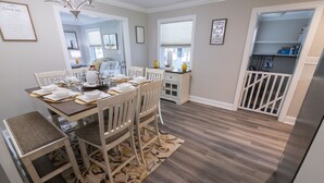 Comedor con una mesa de madera dispuesta para cuatro personas, rodeado de sillas blancas.