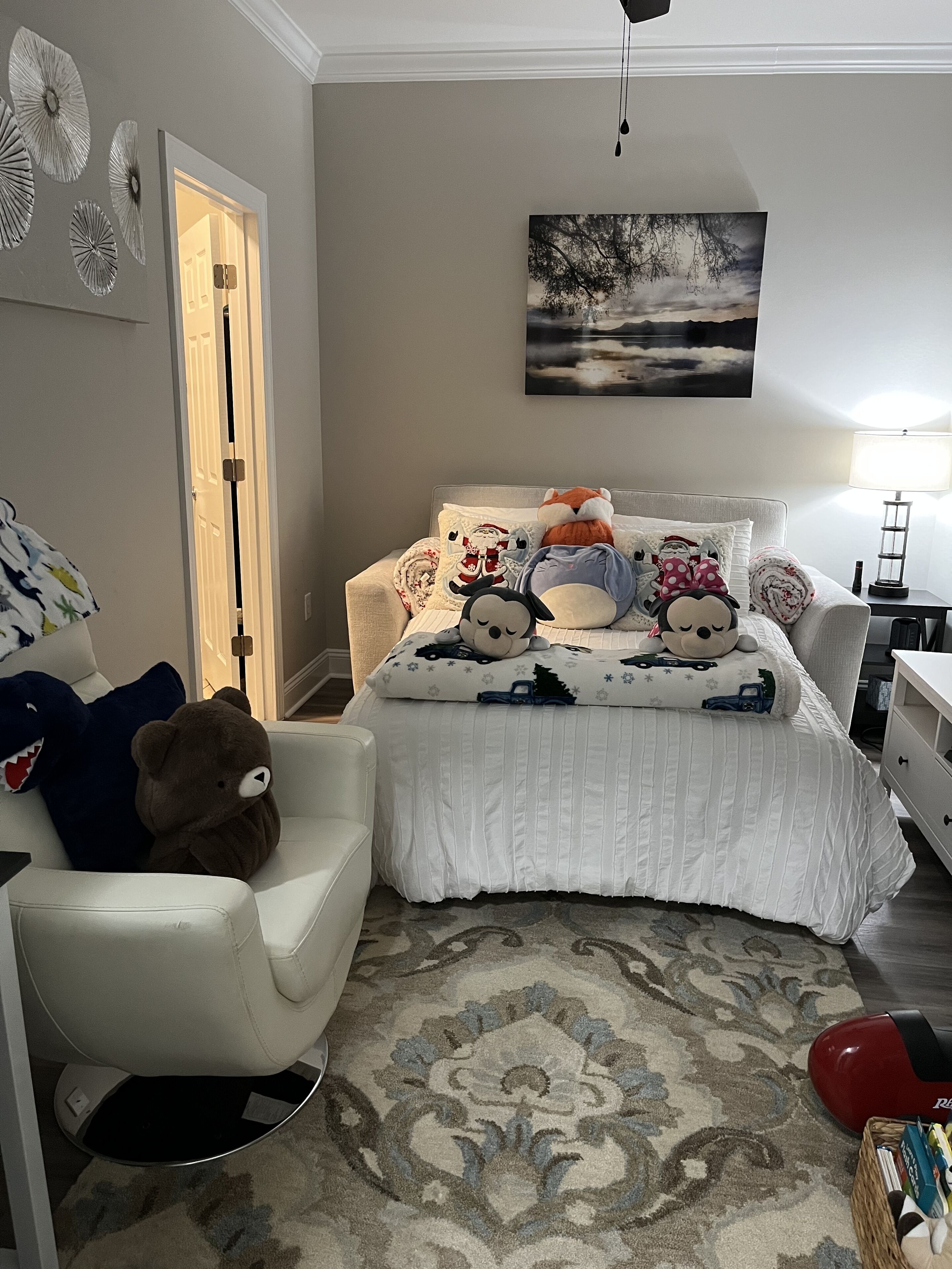 Un dormitorio con una cama, una silla, una alfombra y un cuadro en la pared.