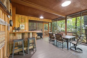 A wooden deck with a bar area, outdoor seating, and a view of the surrounding forest. - 'Make Your Mark' Cozy Sapphire Cabin with Hot Tub (Sapphire)