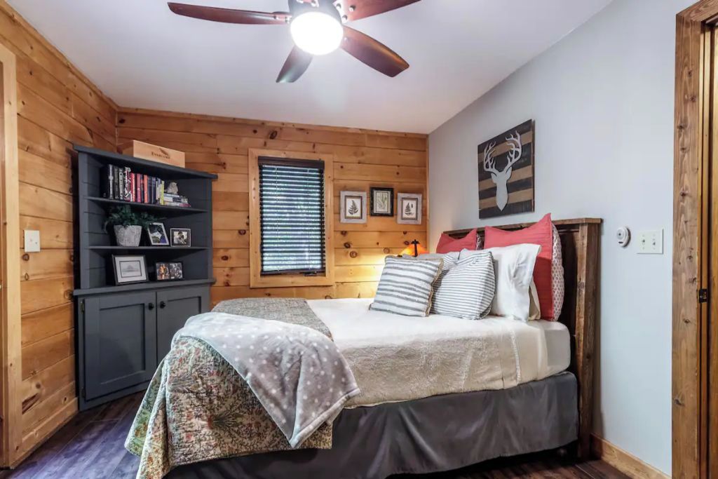 Ein gemütliches Schlafzimmer mit einem Bett, einem Bücherregal und einem Deckenventilator.