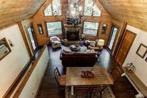 Une pièce spacieuse de style loft, avec un haut plafond, une cheminée, un coin repas et de grandes fenêtres.