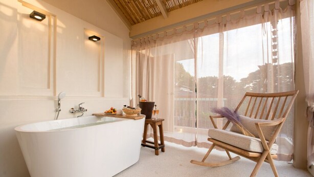 Une salle de bain moderne avec une baignoire sur pieds, un fauteuil à bascule en bois et un petit tabouret.