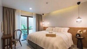 Habitación de hotel con una cama grande, una mesita, una silla y vistas al exterior a través de una ventana.